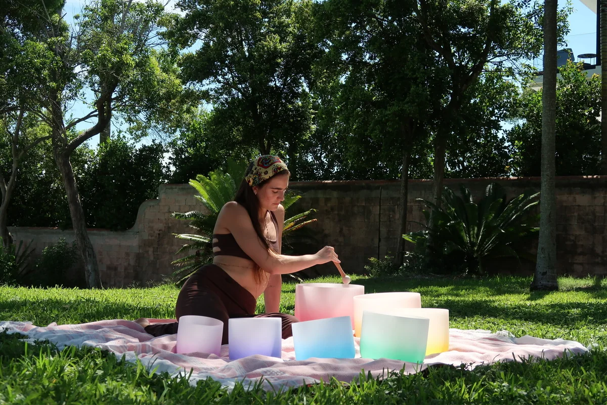 Tatiana Gentile playing crystal singing bowls on a pink blanket