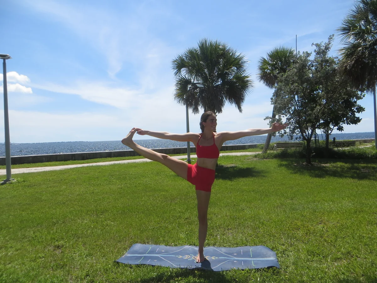 Tatiana Gentile balancing on one leg beside the waterfront, holding the other leg sideways